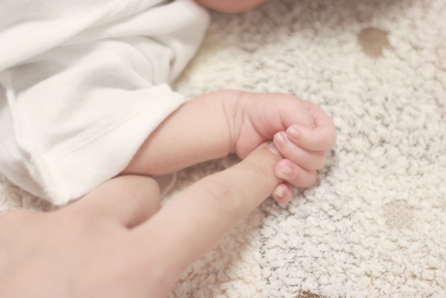 大きな指を握りしめる赤ん坊の手の画像